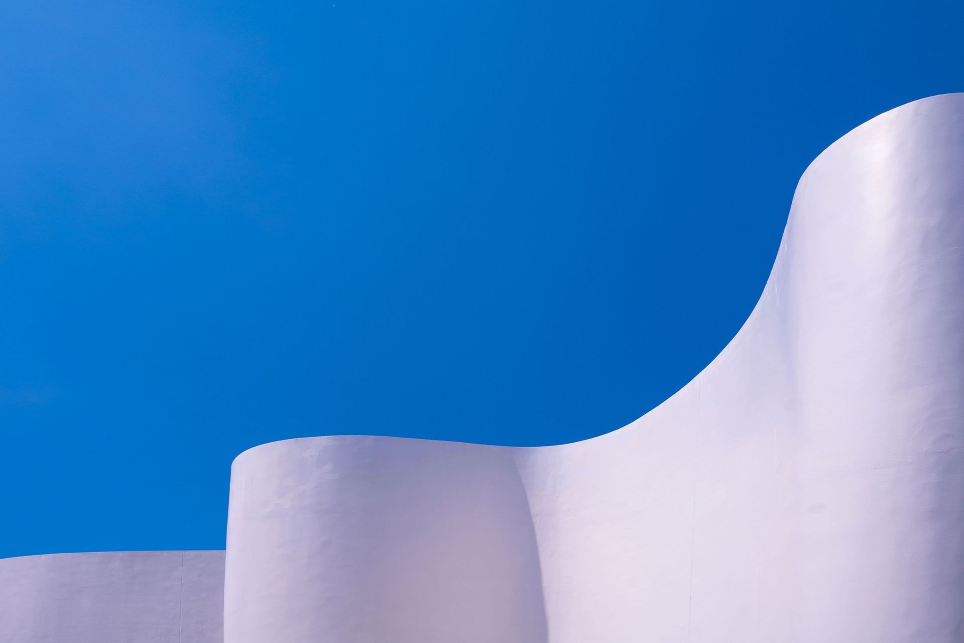 White curve concrete building wall in minimal style against blue sky background, Abstract modern exterior architecture decoration design White curve concrete building wall in minimal style against blue sky background, Abstract modern exterior architecture decoration design